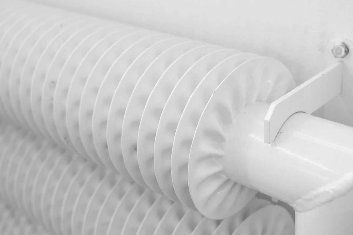 Close-up of a ribbed heating element mounted on a white frame, illustrating where a heating pad would be placed in a hermit crab enclosure