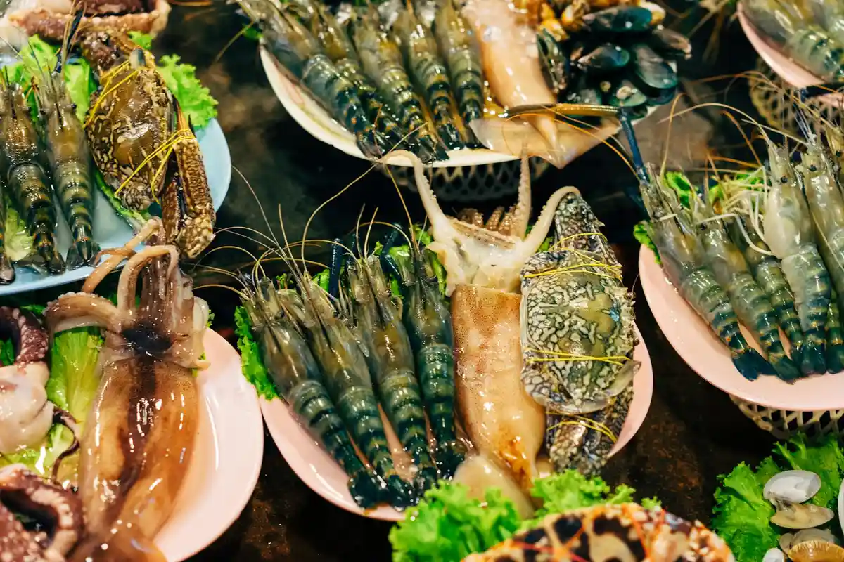Assorted seafood items on plates (shrimp, crab, and other shellfish) illustrating protein sources to consider in a hermit crab’s balanced diet